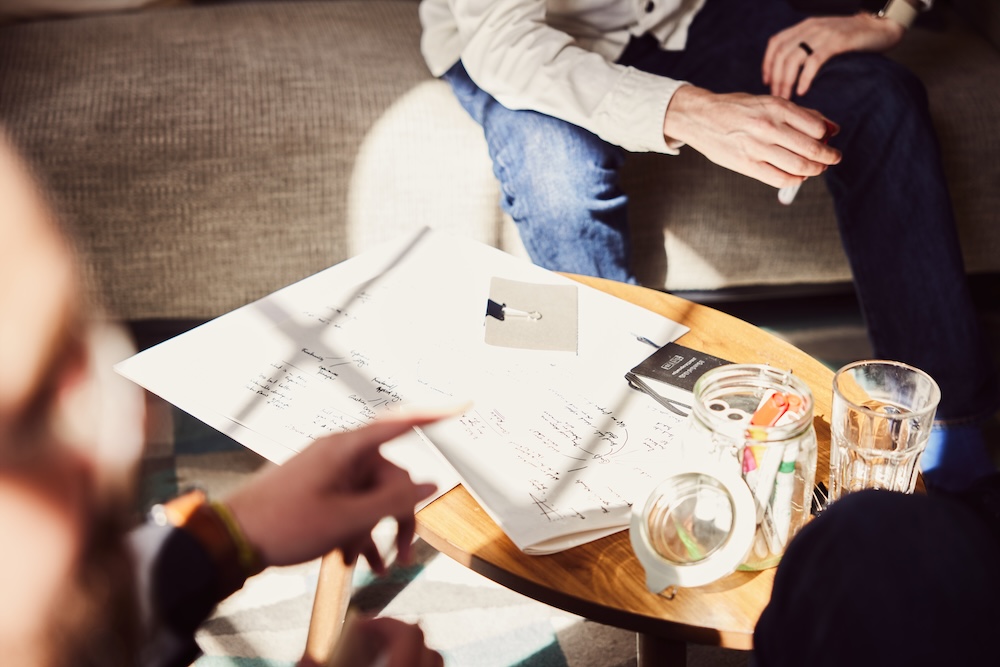 A wooden table with paper and pens sitting on it.